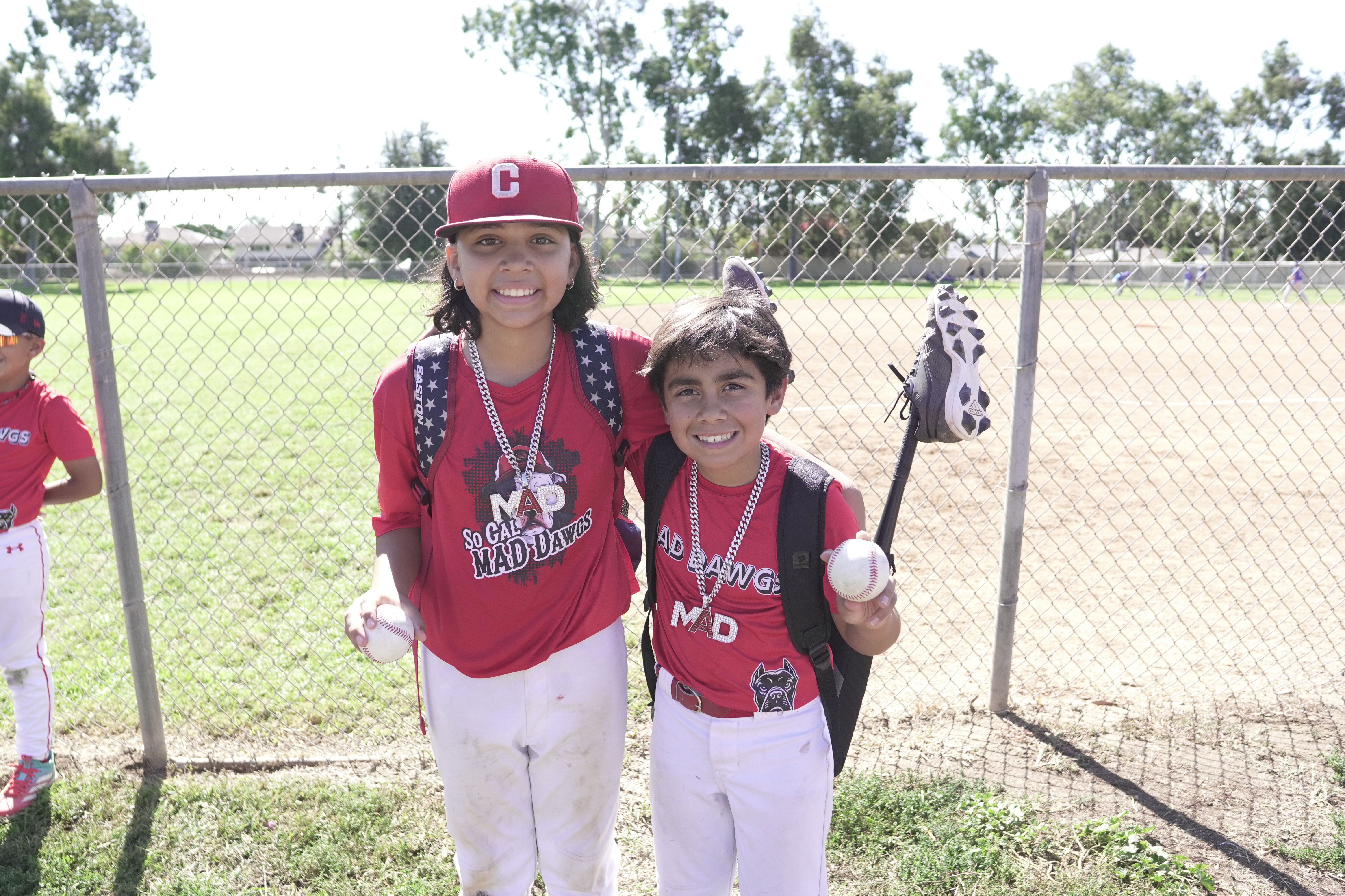 Two MAD Dawgs players smiling with baseball