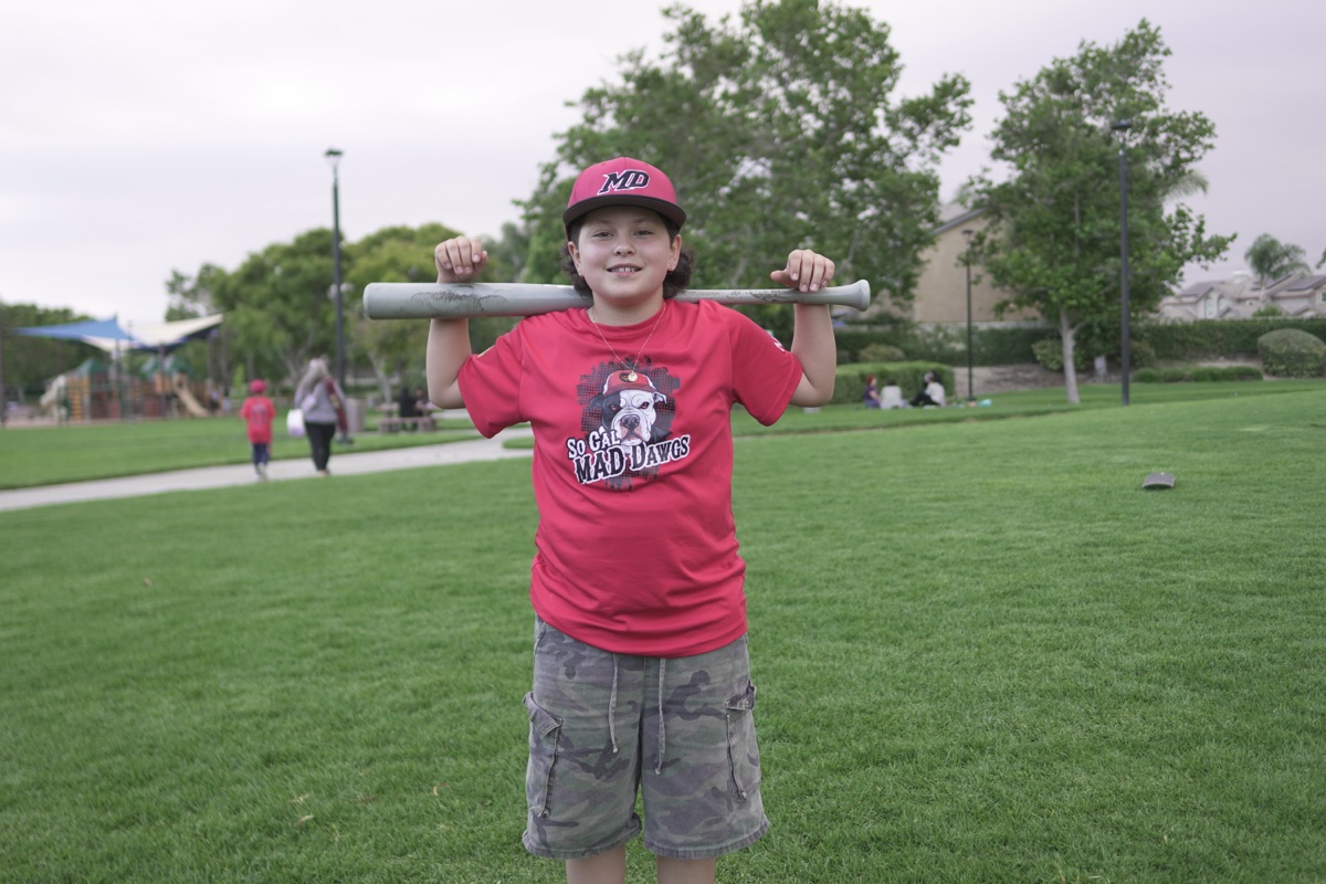 MAD Dawgs player with bat across shoulders smiling