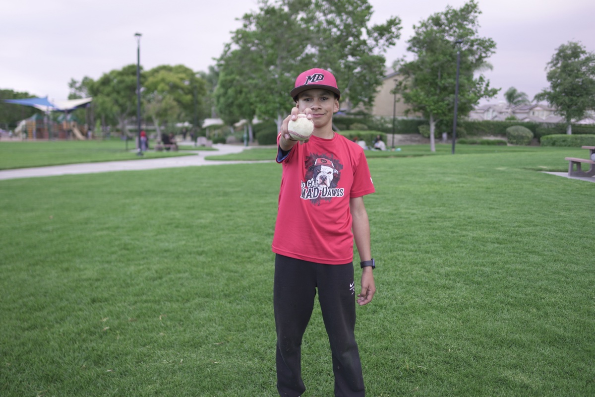 MAD Dawgs player holding up baseball with a smile